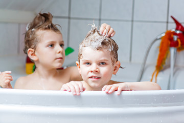 Two little kids boys playing together in bathtub