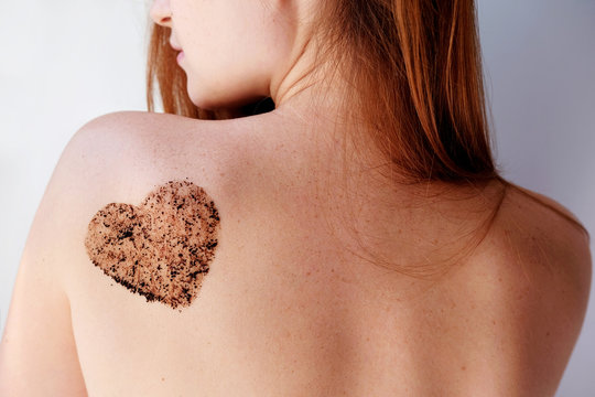 Woman with coffee scrub in a heart shape on back. Close up