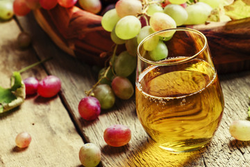 Fototapeta na wymiar Grape juice in glass and berries with leaves, vintage wooden bac