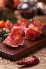 Delicious prosciutto ham on a wooden board with spices.