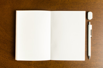 Blank notebook with pencil and eraser on wooden table