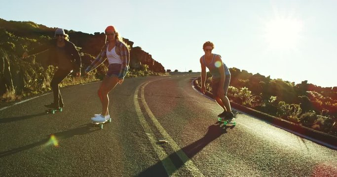 Skateboarders riding down mountain road