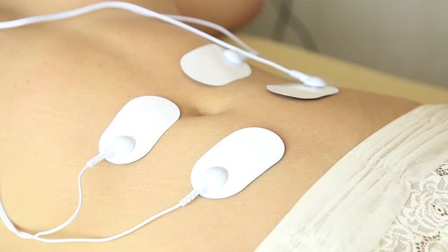 professional electrotherapy on woman body. muscle contraction under the influence of an electric current. close-up patient's stomach
