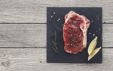 Raw beef steak on dark wooden table background, top view