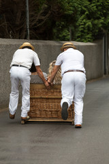 Toboggan riders moving traditional cane sledge downhill on the streets of Funchal. Monte park, Madeira island, Portugal © wjarek