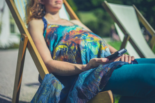 Pregnant woman in deck chair with phone