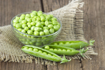 a bowl full of green peas on wooden background