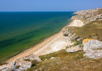 coastline with sandy beach and rocks under a blue sky