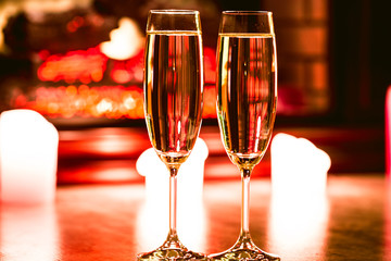 Beautiful two glasses of champagne standing on the table in the background of a blurred room with a decorated Christmas tree and fireplace. Soft focus. Shallow DOF