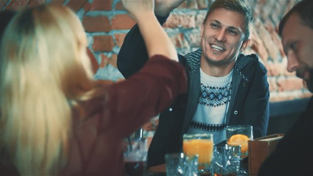 Man and women in bar gives high five HD slow motion video. Group of young people having fun in cafe or party with beverage cocktails