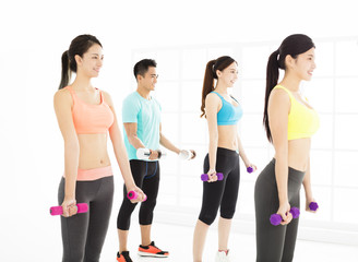 Naklejka premium smiling young fit group stretching in gym