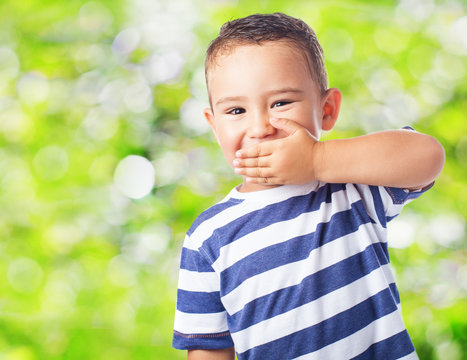 portrait of a cute kid covering his mouth with his hand