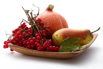 Autumn gifts. Still life with pumpkin, viburnum and pear on wooden plate and white background.