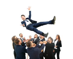 Businessman get thrown into the air by co workers during celebra