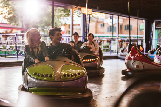 Young people driving bumper car at amusement park
