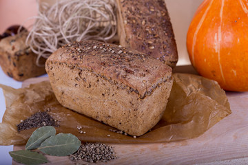 a loaf of bread on the background of cutting boards and other bread and pumpkin,