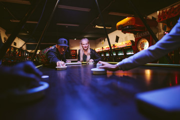 Young man and woman playing air hockey game