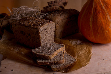 a loaf of bread on the background of cutting boards and other bread and pumpkin,