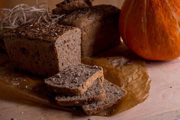 a loaf of bread on the background of cutting boards and other bread and pumpkin,