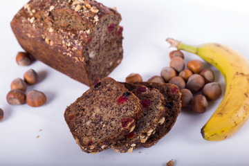loaf of bread with bananas and hazelnuts on a white background