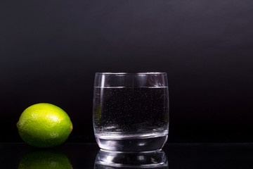 a glass of water, studio photo of lemon lime, on black background, isolated