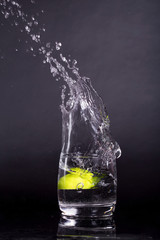 Falling in a glass of lemon, lime, splash on black background, isolated, water drop