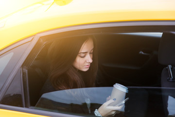 Charming brunette looking in phone at yellow taxi
