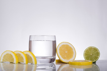 Splashes of water, lemon lime falling into a glass, isolated, reflection, white background, water drop