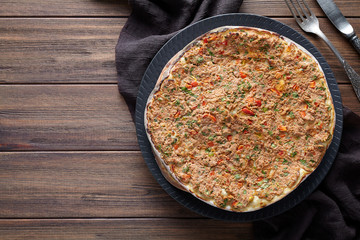 Lahmacun homemade turkish delicious pizza with minced beef or lamb meat, paprika, tomatoes, cumin spice, parsley baked spicy middle eastern arabian food on rustic wooden table background