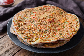 Lahmacun turkish delicious pizza with minced beef or lamb meat, paprika, tomatoes, cumin spice, parsley baked spicy middle eastern arabian food on rustic wooden table background