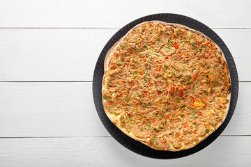 Lahmacun traditional turkish pizza with minced beef or lamb meat, paprika, tomatoes, cumin spice, parsley baked spicy middle eastern arabian food on white wooden table background