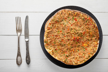 Lahmacun turkish pizza with minced beef or lamb meat, paprika, tomatoes, cumin spice, parsley baked spicy middle eastern arabian food on white wooden table background