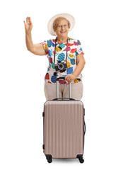 Cheerful mature tourist with a suitcase waving