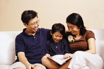 Family with one son, sitting on sofa, looking at book