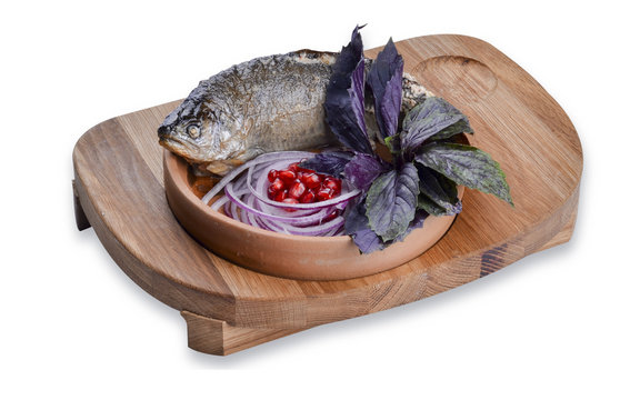 Isolated fried trout in a frying pan and a wooden board ketsi