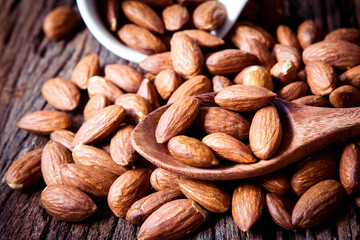 close up Peeled almonds nut in spoon on wooden  background