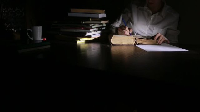 Smart man studying late at night, he is sitting at desk and reading book
