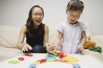 Mother and daughter, playing with toys, smiling