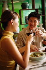 Couple dining in Chinese restaurant, toasting with wine glasses