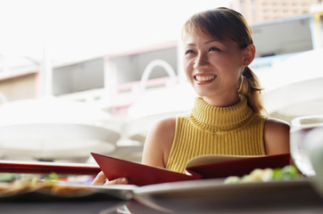 Woman in cafe, holding menu, looking away, low angle view