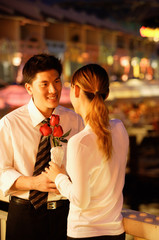 Couple standing face to face, woman holding roses