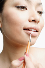 Young woman using lipstick brush