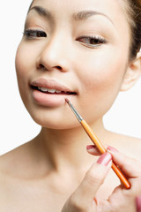 Young woman using lipstick brush, portrait