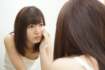 Young japanese woman treating her skin in a bathroom