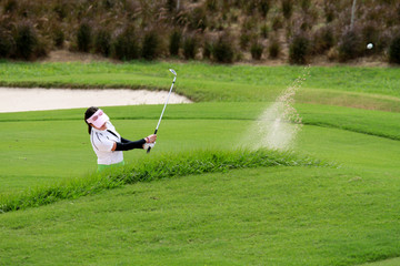 The women golfers hit golf balls off the sand motion blur