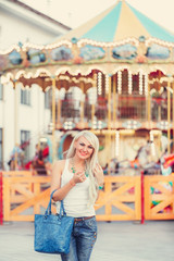 cheerful young woman walking at the amusement park against the b