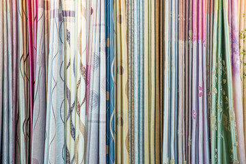 Colorful curtain samples hanging from hangers on a rail in a dis