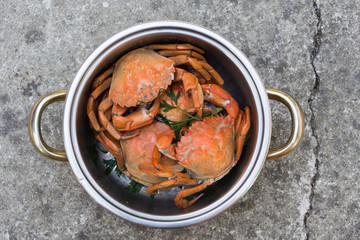 Boiled red crabs in a pot with herbs, top view