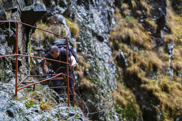Obraz premium Caucasian hiker climbing on a safety chains through a very diffi