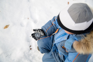 Little boy winter oriented by the compass. Compass lies in his hands. Snow on the glove boy
